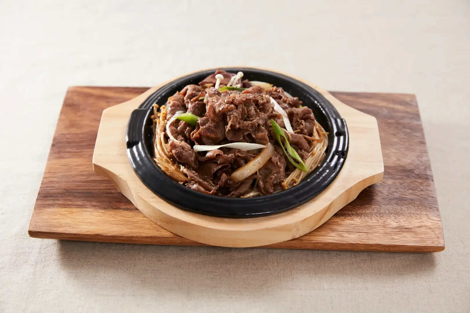 Bulgogi on a metal pan on top of wooden plate
