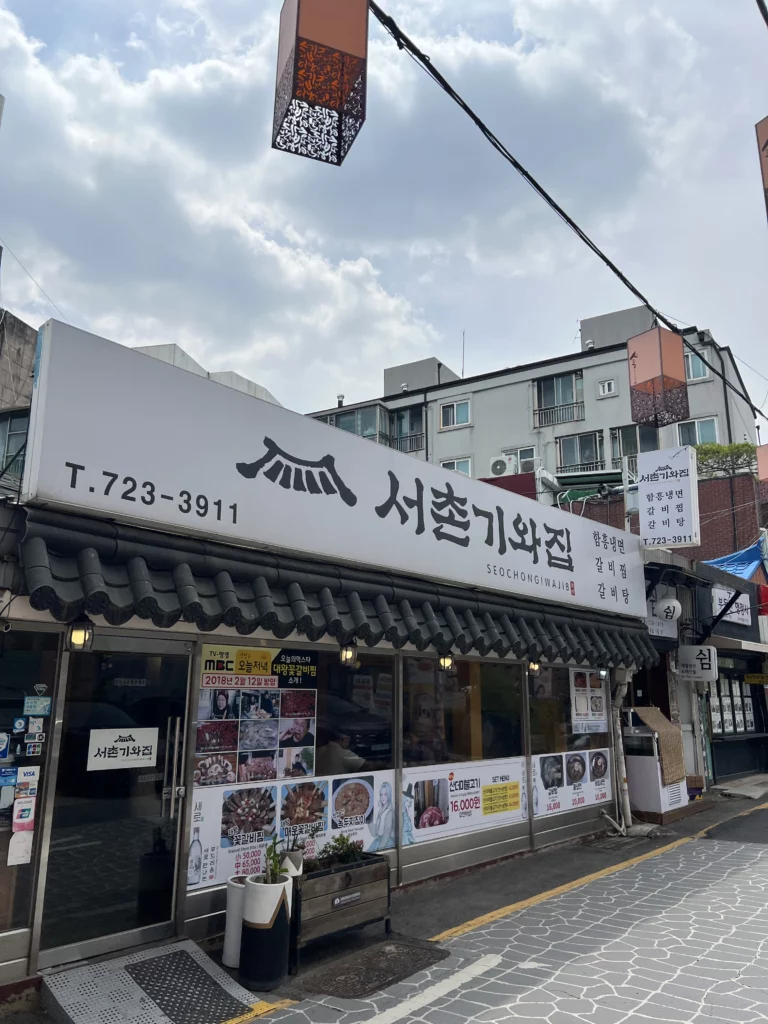 Seochon Giwajip traditional Korean restaurant exterior in Seoul with authentic tile roof design displaying bulgogi and Korean food menu photos on the storefront.