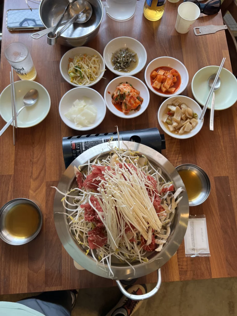 Authentic Korean bulgogi meal at Seochon Giwajip Seoul restaurant featuring marinated beef with bean sprouts and traditional banchan side dishes including kimchi and pickled vegetables.