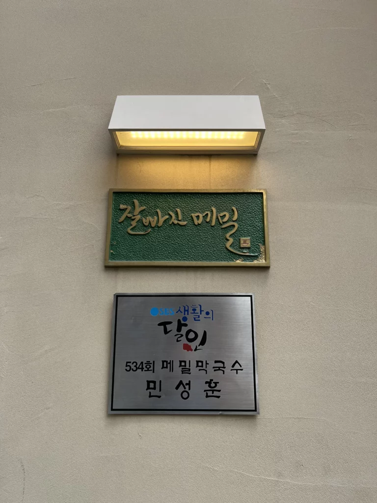 Korean restaurant signage displaying Jalppaejin Memil name plaque and traditional buckwheat noodle makguksu establishment recognition at authentic Seoul restaurant.