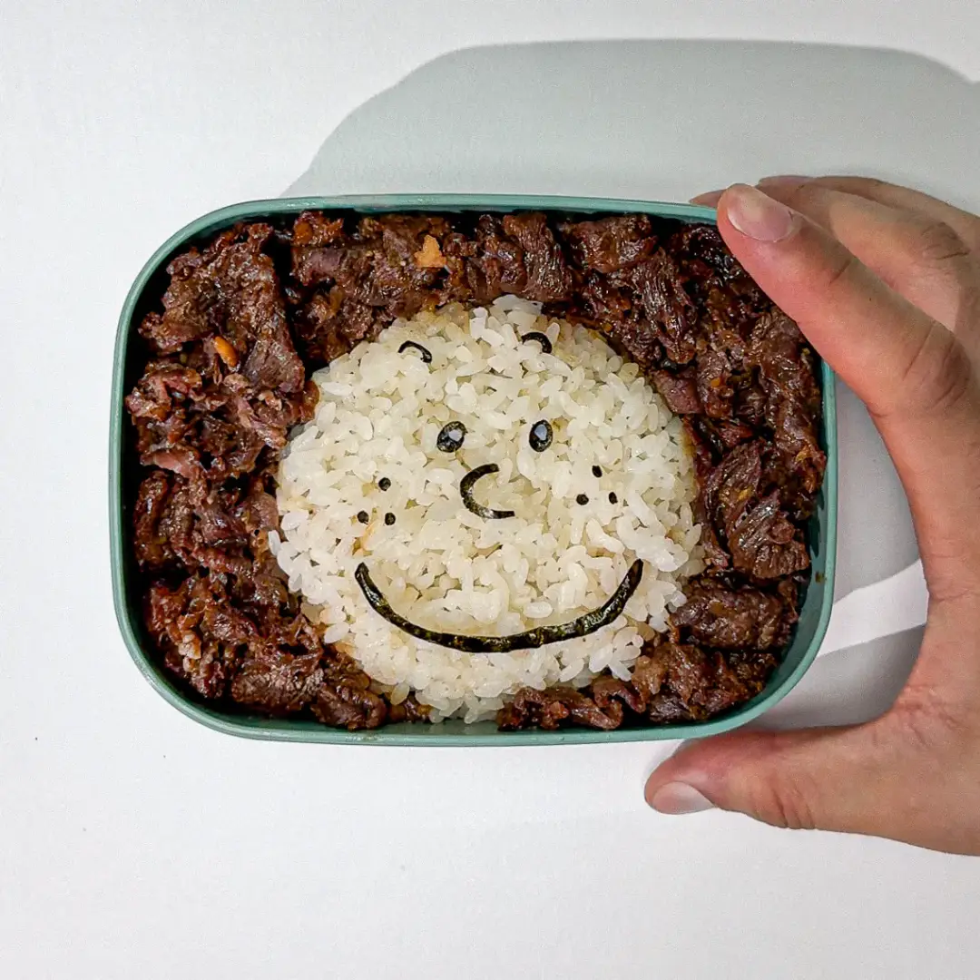 Cute Korean lunchbox with Bulgogi beef and rice decorated with a smiling face.