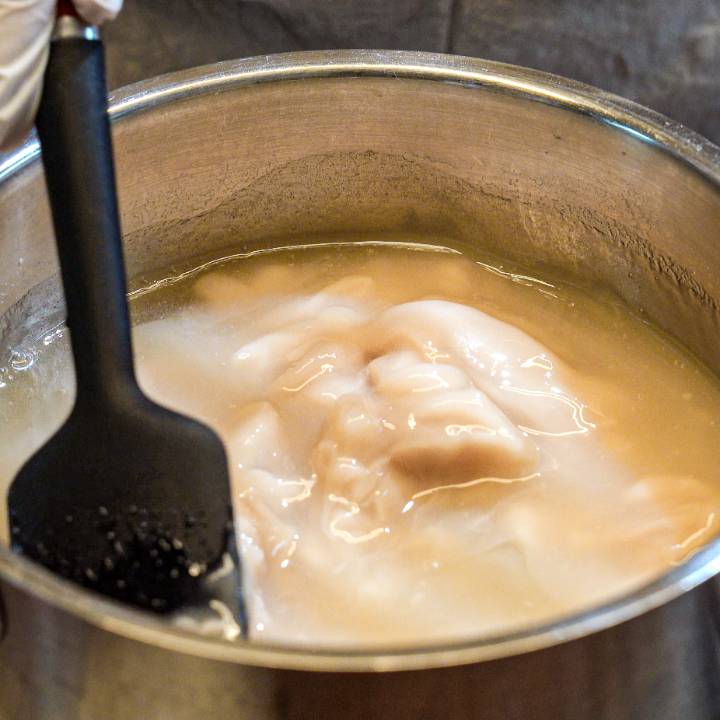 Stirring soft sweet bean mixture while it thickens in a pot during yanggaeng preparation.
