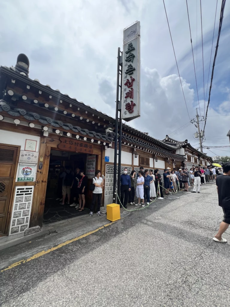 Long queue of visitors waiting outside Tosokchon Samgyetang traditional hanok restaurant near Gyeongbokgung Palace in Seoul, famous for authentic Korean ginseng chicken soup.