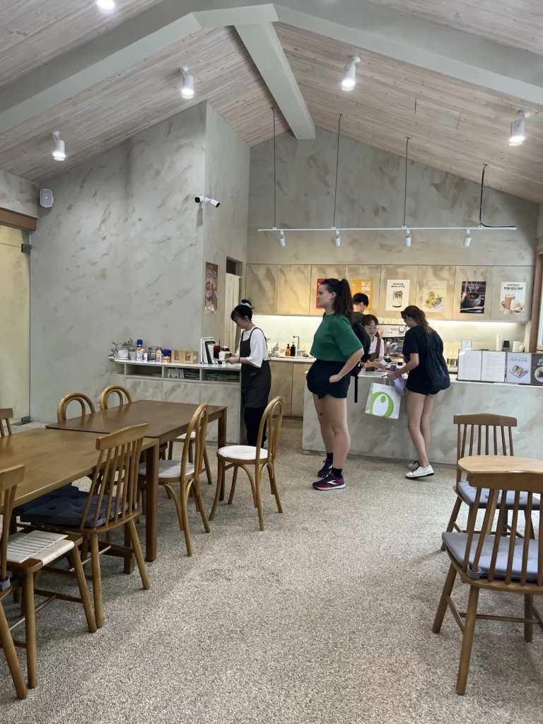 Customers ordering at the counter of Bukhansan Lounge mountain view cafe featuring minimalist interior design with concrete walls, wooden furniture, and track lighting at Bukhansan National Park in Seoul.