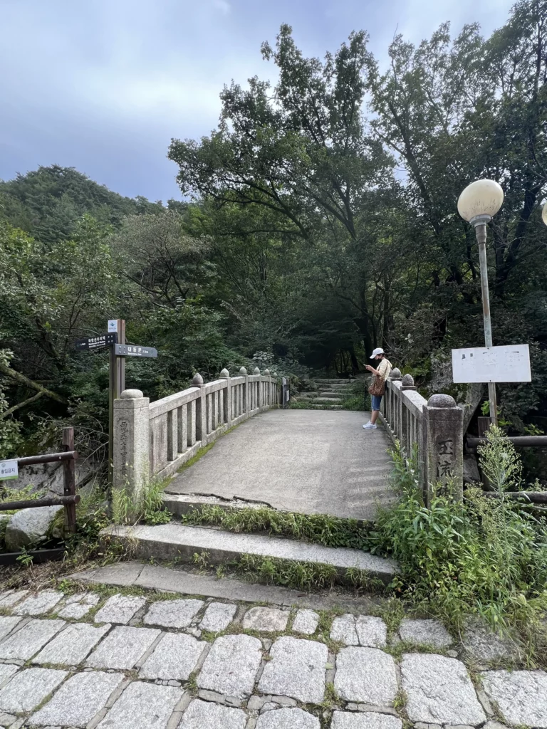 Scenic walking path and bridge leading to Seonungak hanok cafe surrounded by lush forest at Bukhansan National Park Seoul.