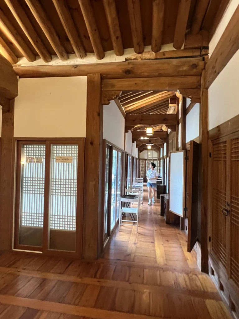 Seonungak hanok cafe traditional Korean corridor with hanji lattice doors, exposed wooden beam architecture, and natural light at Seoul's largest private hanok near Bukhansan Mountain.