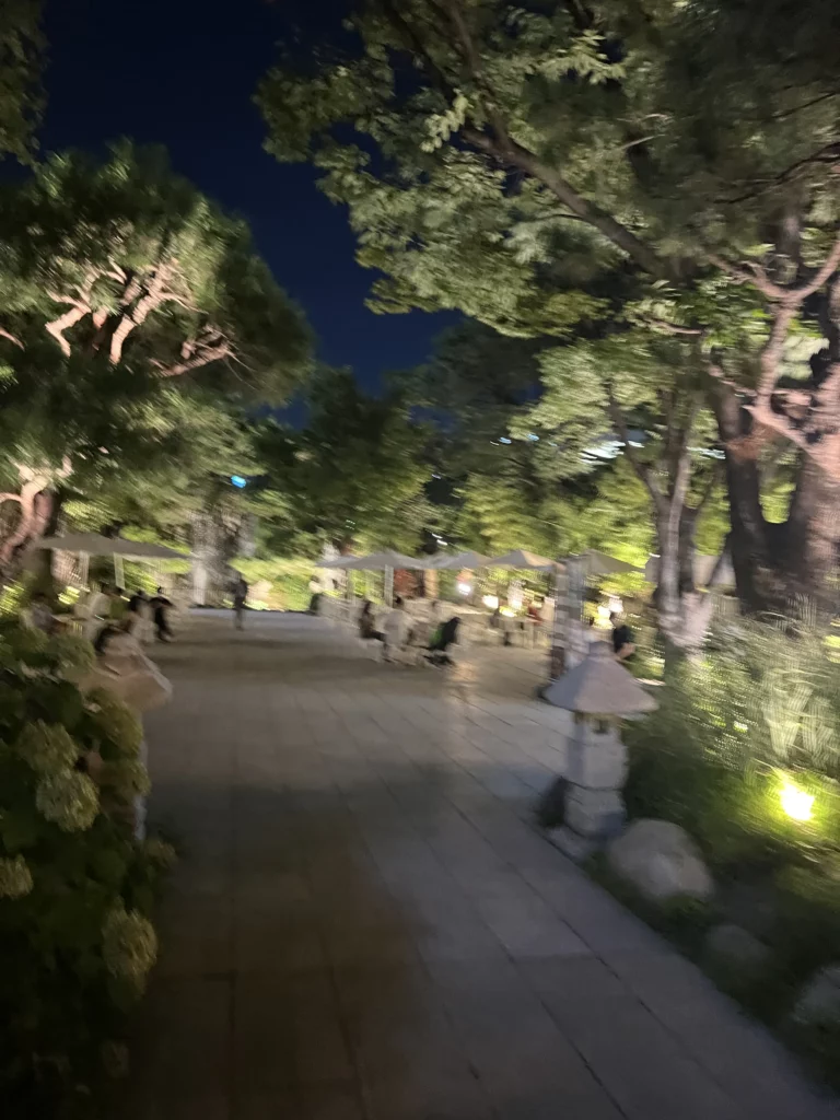 Illuminated Korean garden pathway at night with traditional landscaping at Samwon Garden restaurant in Gangnam Seoul creating serene dining atmosphere.