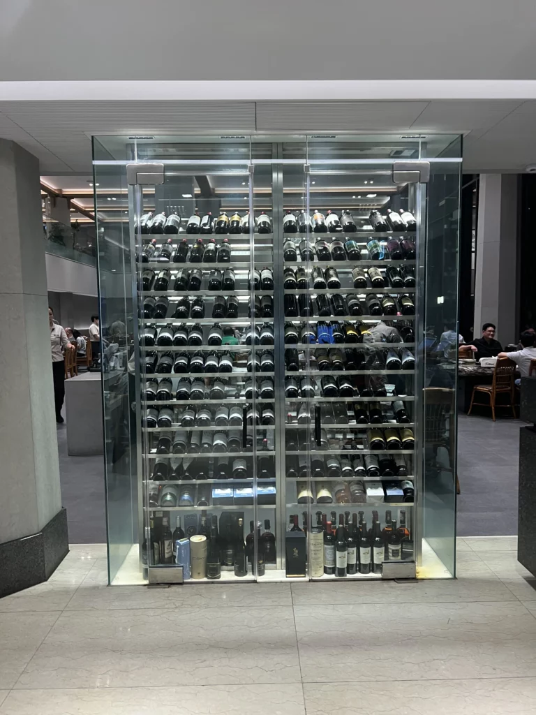 Glass-enclosed wine cellar with extensive collection at Samwon Garden showcasing premium dining atmosphere in Gangnam Seoul Korean BBQ restaurant.