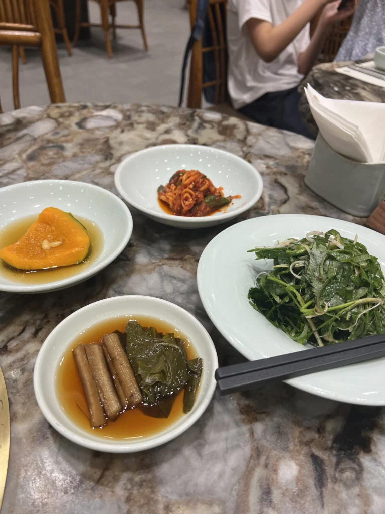 Assorted Korean banchan side dishes at Samwon Garden Seoul including pickled radish, kimchi, braised kelp, and fresh vegetables served with Hanwoo galbi BBQ.