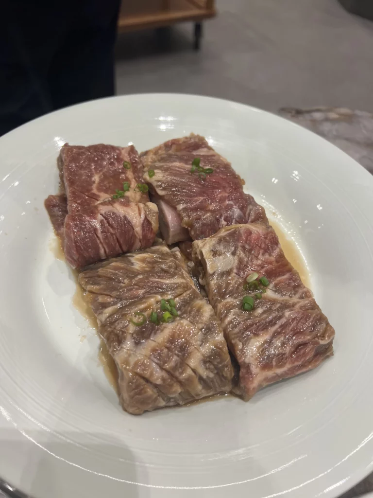Premium Hanwoo galbi beef short ribs with exceptional marbling served on a white plate at Samwon Garden Seoul, ready for traditional Korean BBQ charcoal grilling.