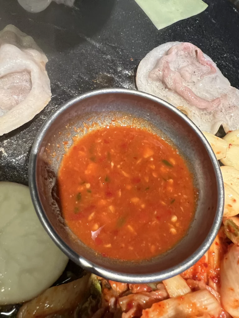 Spicy dipping sauce with garlic for samgyeopsal on stone grill plate at Seokam Saeng Sogeum-gui Korean BBQ Seoul.