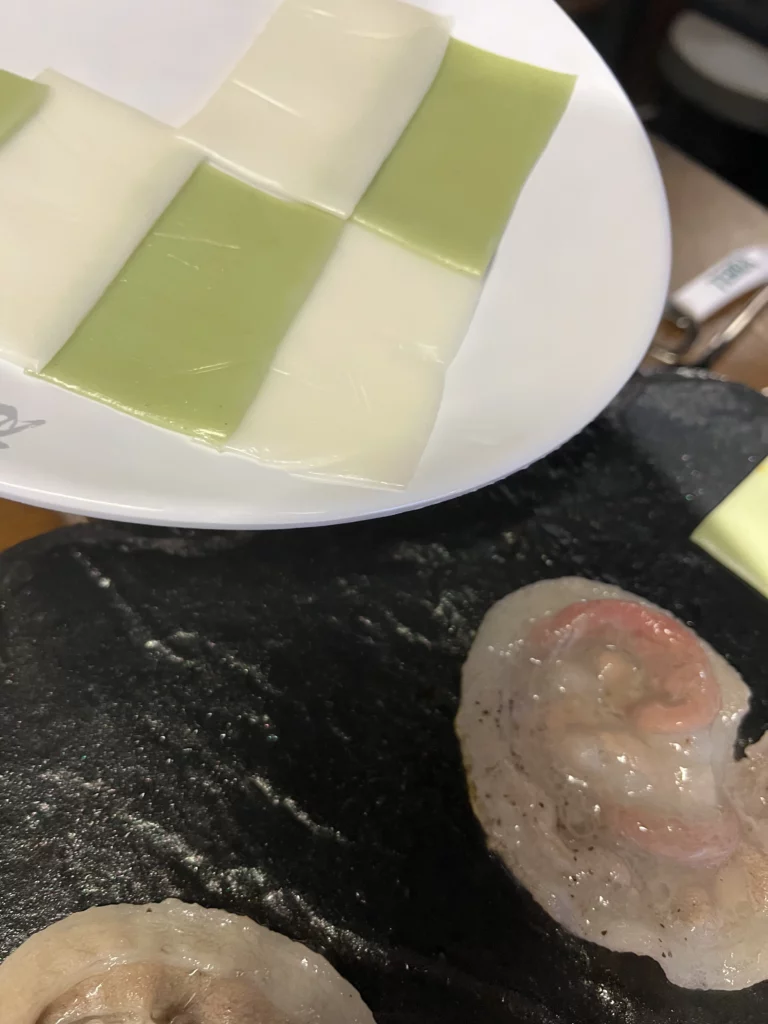White and green rice cakes with grilling pork belly on volcanic stone grill plate at Seokam Saeng Sogeum-gui Korean BBQ Seoul.
