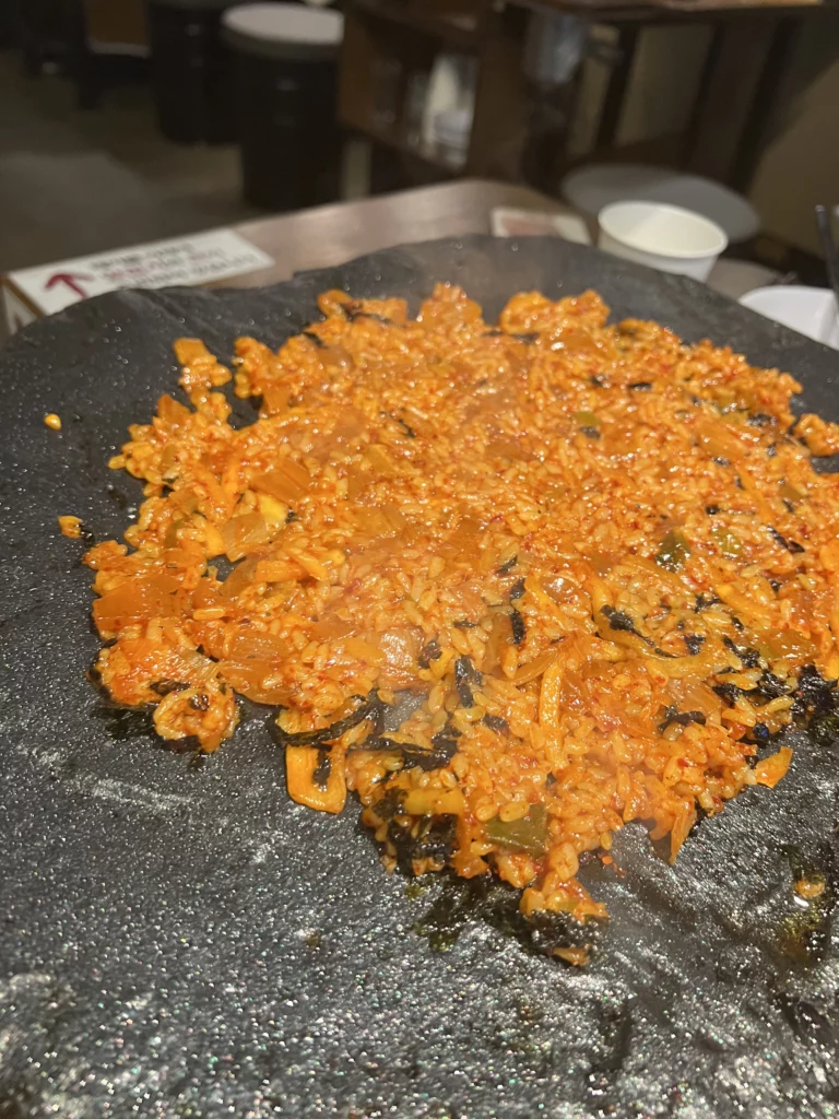 Crispy golden samgyeopsal pork belly grilled on volcanic stone plate at Seokam Korean BBQ restaurant in Seoul.