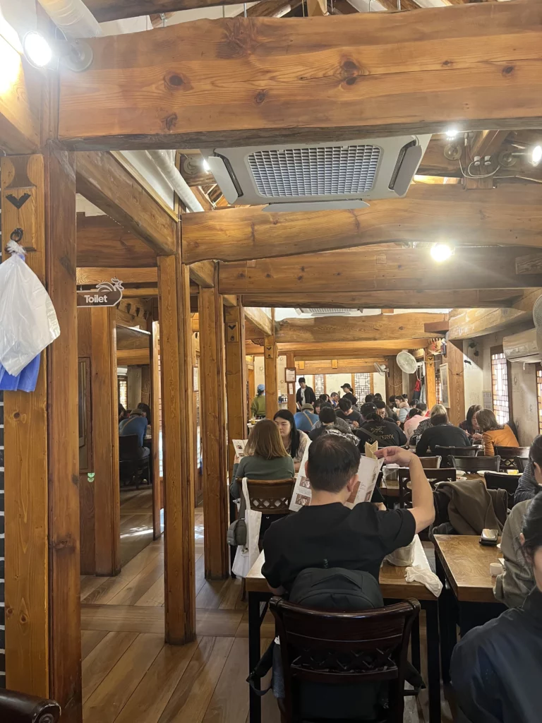 Traditional hanok interior dining room at Tosokchon Samgyetang with wooden beams and pillars, diners enjoying authentic Korean ginseng chicken soup near Gyeongbokgung Palace Seoul.