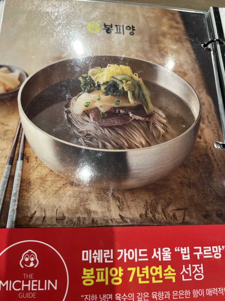 Pyongyang-style naengmyeon cold noodles in metal bowl at Bongpiyang Michelin Bib Gourmand Korean BBQ restaurant Seoul.