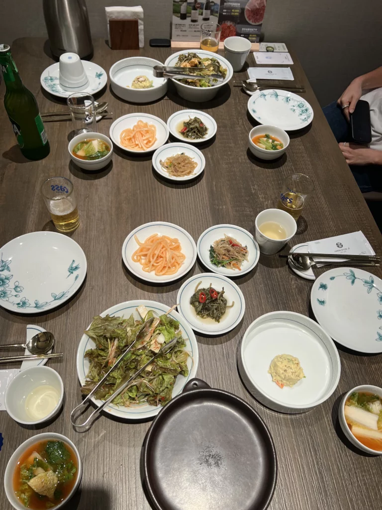 Complete Korean BBQ table setting with lettuce wraps and banchan side dishes ready for pork galbi grilling at Bongpiyang Michelin restaurant in Seoul.