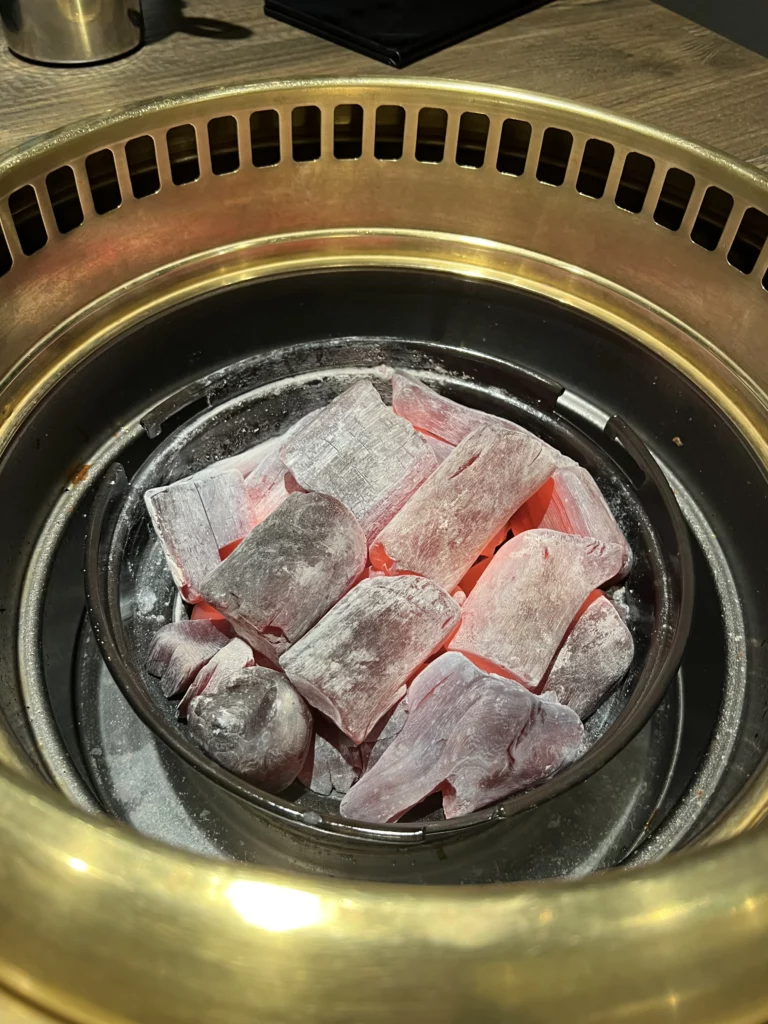 Glowing red charcoal in traditional Korean BBQ grill at Bongpiyang ready for cooking premium pork galbi.