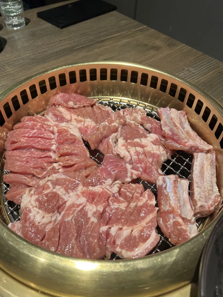 Premium pork ribs with diamond-score pattern arranged on charcoal grill at Bongpiyang Michelin Bib Gourmand Korean BBQ restaurant.