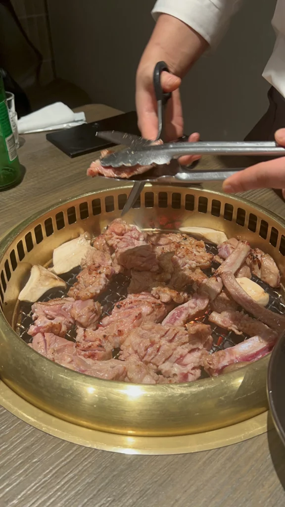 Marinated pork ribs grilling on charcoal grill with rice cakes at Bongpiyang Korean BBQ restaurant in Sinsa-dong Seoul.