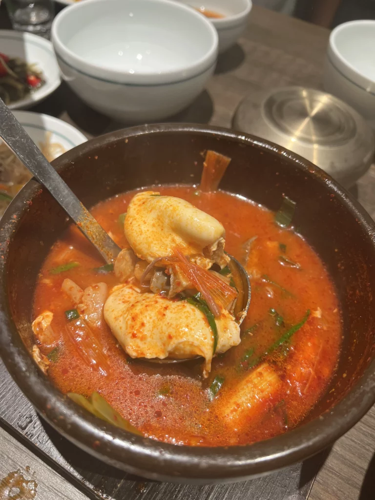 Spoonful of kimchi jjigae with fermented napa cabbage in red chili broth at Bongpiyang Korean BBQ restaurant.