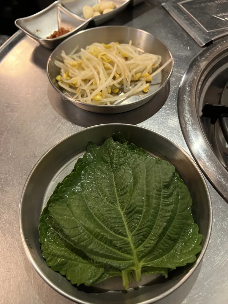 Fresh Korean sangchu lettuce leaves and bean sprouts banchan side dishes for wrapping spicy jjukkumi at Haega Jjukkumi Sinsa-dong Seoul.