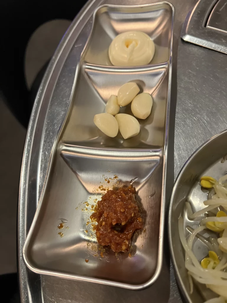 Raw garlic cloves and ssamjang Korean fermented soybean paste condiments for jjukkumi ssam wraps at Haega Jjukkumi Sinsa-dong Seoul.