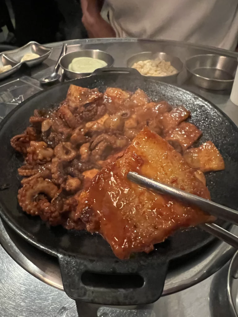 Caramelized samgyeopsal pork belly and jjukkumi webfoot octopus glazed in sweet gochujang sauce on iron grill at Haega Jjukkumi Sinsa-dong Seoul.