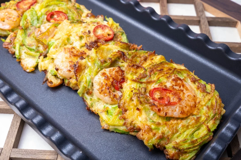 shrimp and vegetable Korean Assorted Jeon on griddle pan, topped with sliced red chili