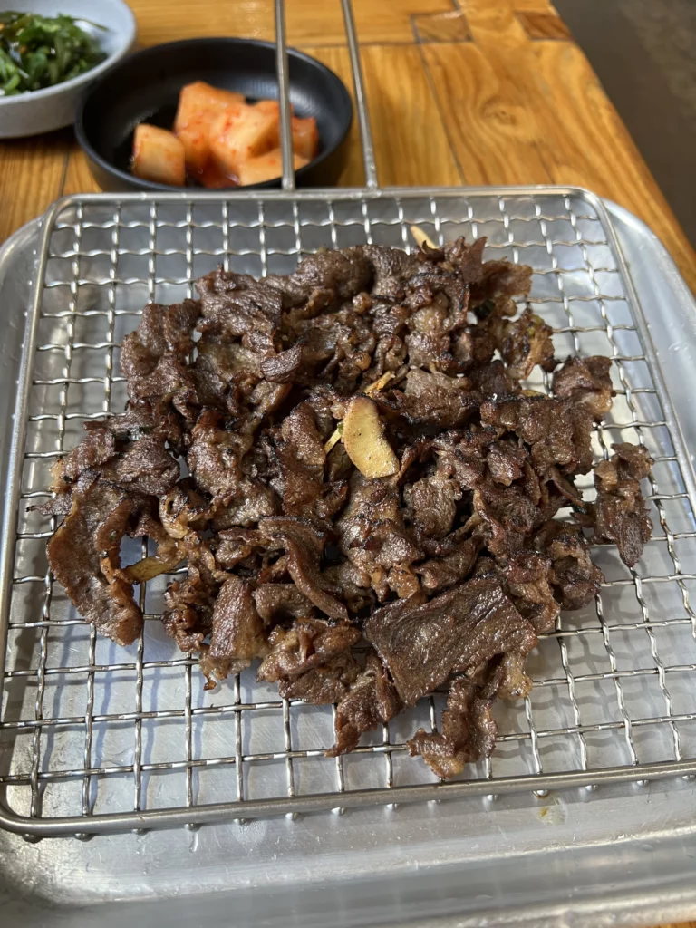 Grilled bulgogi marinated beef on stone grill at Nunnamu-jip Bukchon restaurant in Seoul Korea with traditional Korean side dishes.