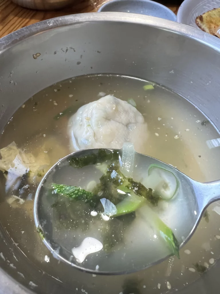 Traditional mandu-guk Korean dumpling soup with clear broth and vegetables served at Nunnamu-jip Bukchon restaurant in Seoul Korea.