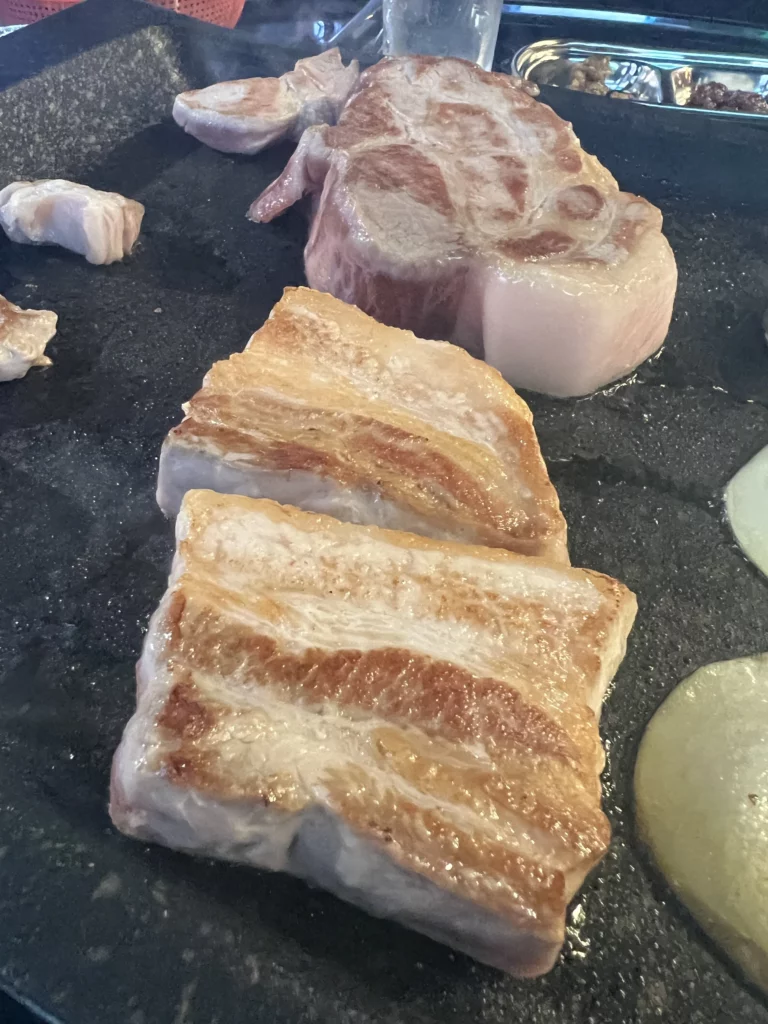 Perfectly grilled 22-day aged samgyeopsal and moksal with caramelized golden-brown edges at Gimsukseoung Korean BBQ restaurant in Seoul.