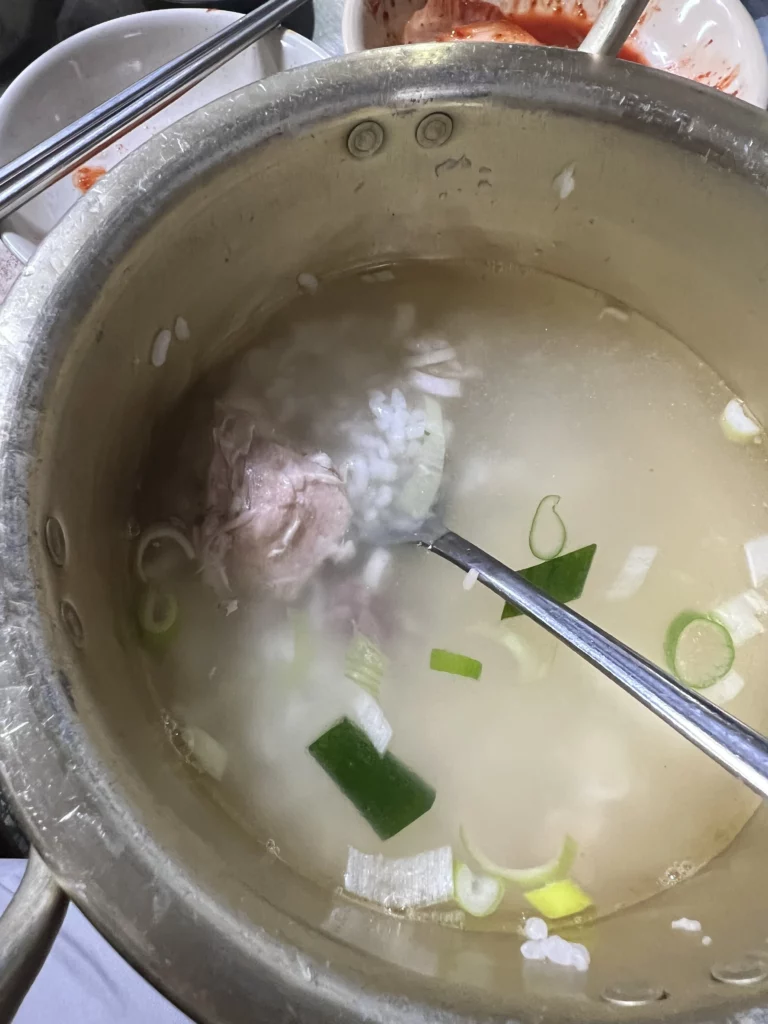 Dak Baeksuk Korean boiled chicken soup with milky white garlic broth and green onions at Sarangbang Kalguksu Seoul restaurant.