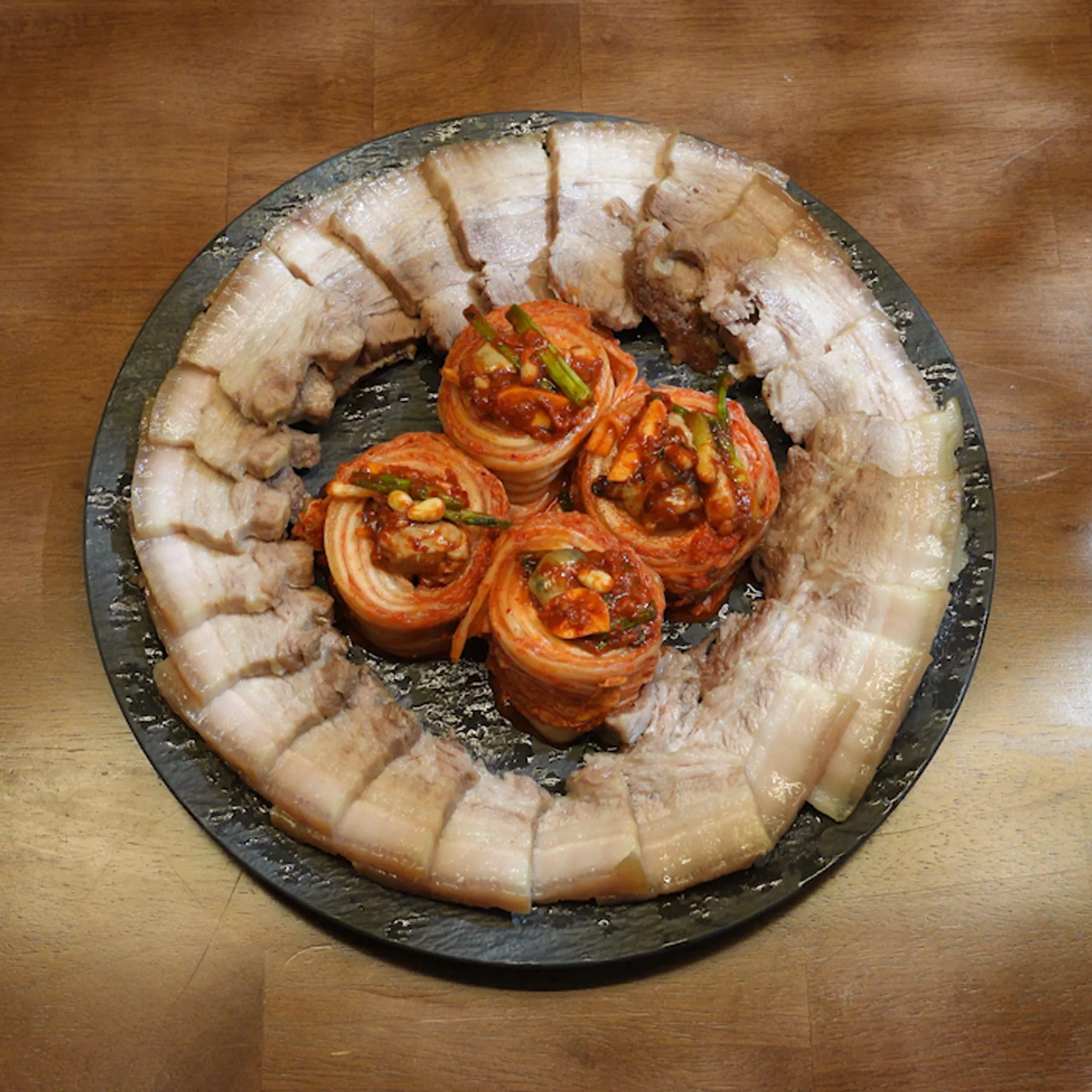 Plated Korean boiled pork with kimchi arranged in traditional style.