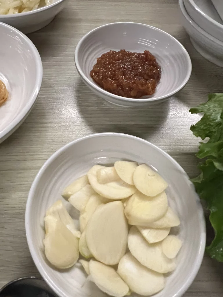 Sliced garlic ssamjang sauce and fresh lettuce leaves for wrapping samgyeopsal at Moosik Korean BBQ restaurant in Sinsa-dong Gangnam Seoul.