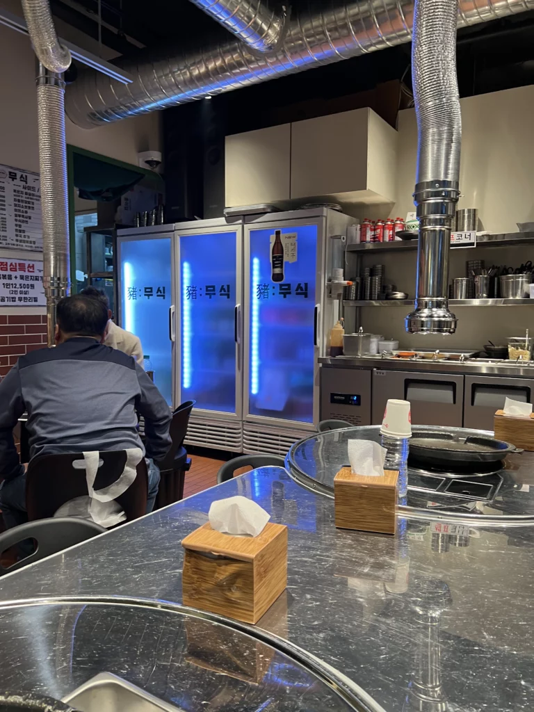Interior dining area at Moosik samgyeopsal restaurant with blue LED refrigerators and grill tables in Sinsa-dong Gangnam Seoul Korea.