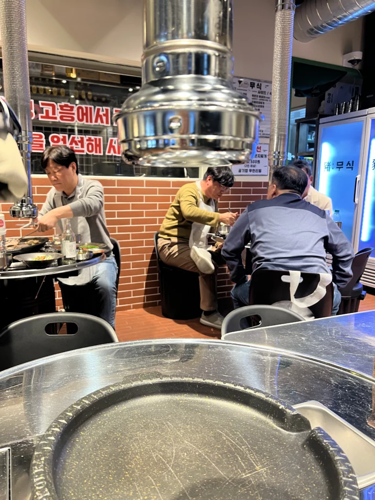 Interior dining area at Moosik samgyeopsal restaurant showing grill tables and customers enjoying Korean BBQ in Sinsa-dong Gangnam Seoul.