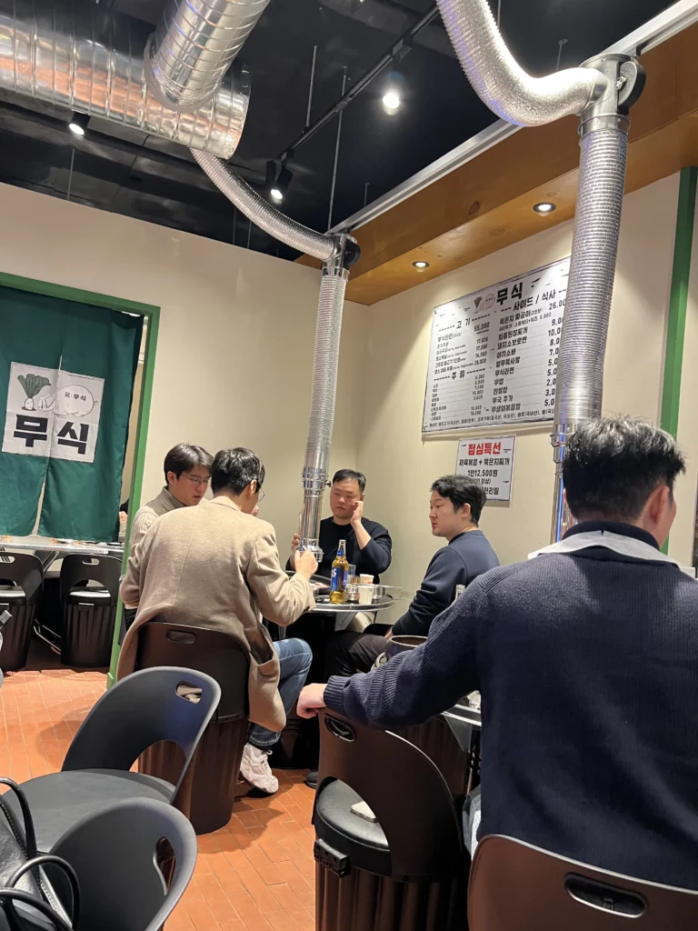 Customers dining at Moosik restaurant interior with ventilation system and menu board in Sinsa-dong Gangnam Seoul Korea.
