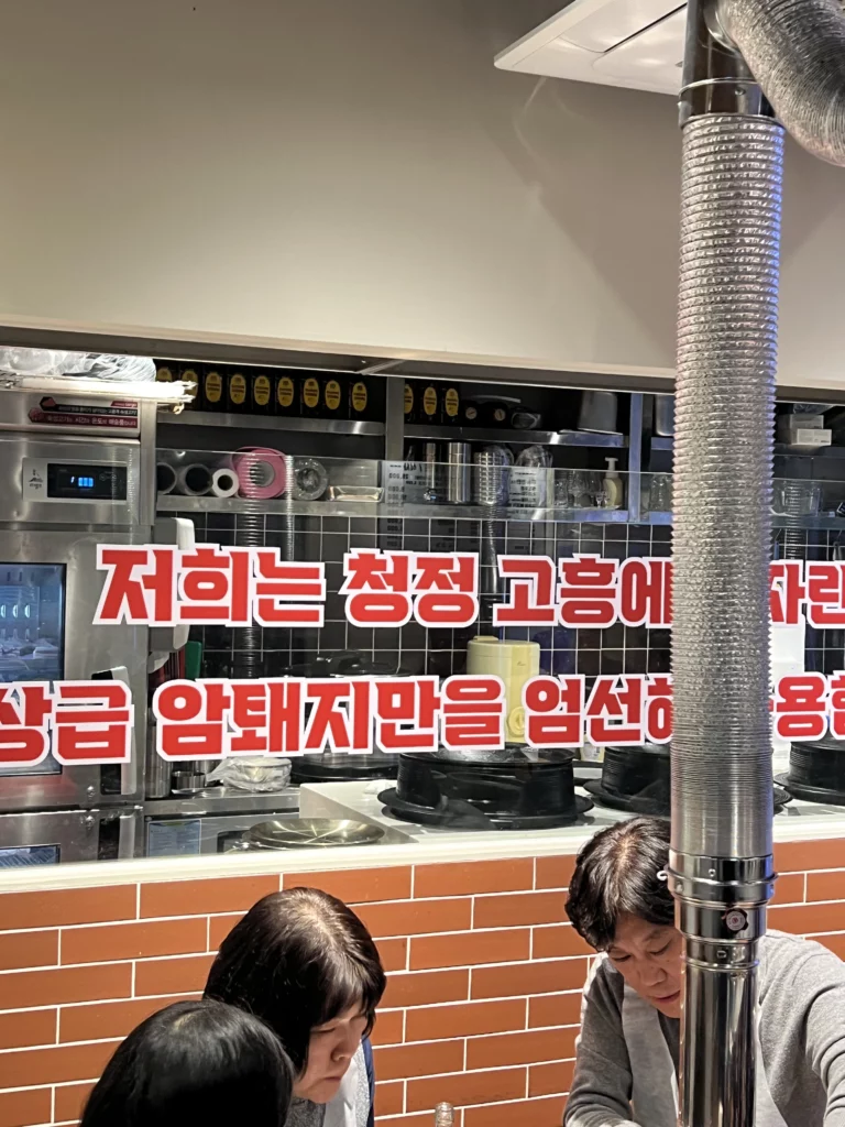 Customers dining at Moosik interior with ventilation system and Korean signage in Sinsa-dong Gangnam Seoul authentic samgyeopsal restaurant.