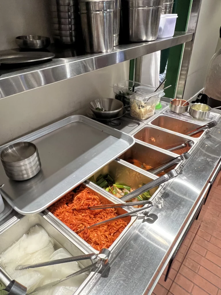 Self-service banchan station with kimchi pickled radish and Korean side dishes at Moosik authentic samgyeopsal restaurant in Sinsa-dong Gangnam Seoul.