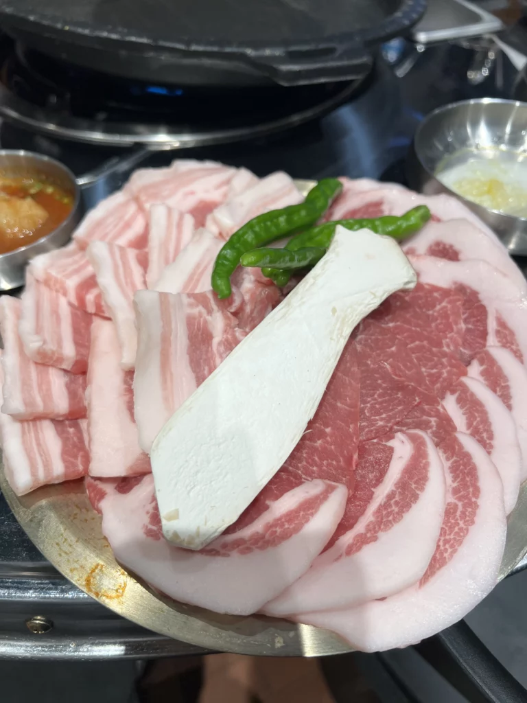 Fresh samgyeopsal pork belly platter with tofu and green chili peppers served at Moosik authentic Korean BBQ restaurant in Sinsa-dong Gangnam Seoul.