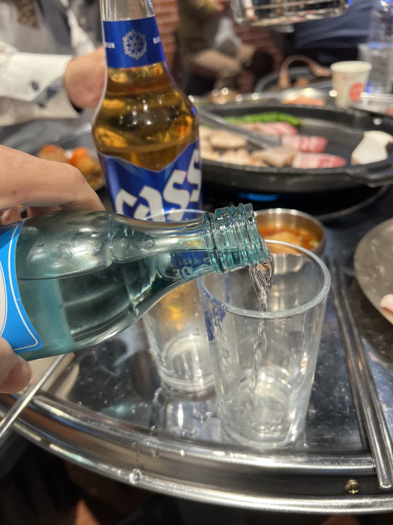 Pouring soju into glass for samgyeopsal pairing at Moosik authentic Korean BBQ restaurant in Sinsa-dong Gangnam Seoul.