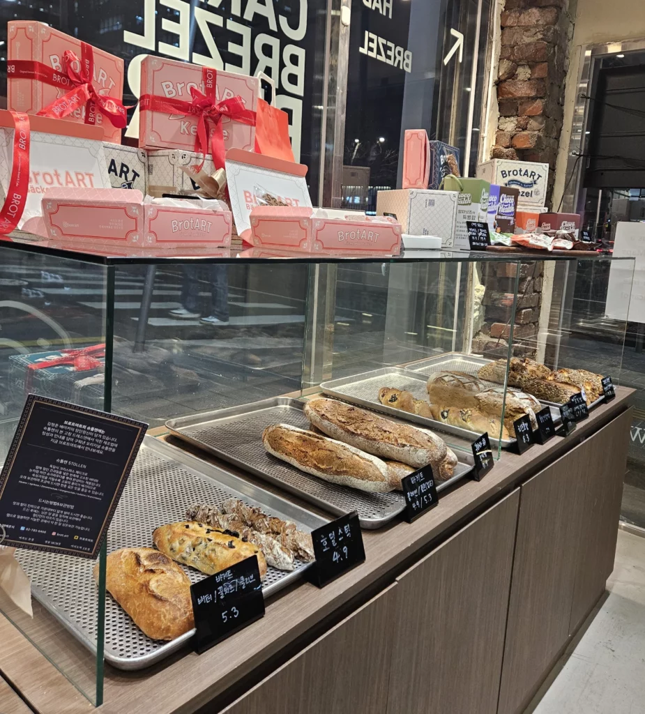 Rustic bread selection and premium gift boxes displayed in a modern bakery cafe specializing in European-style baked goods.