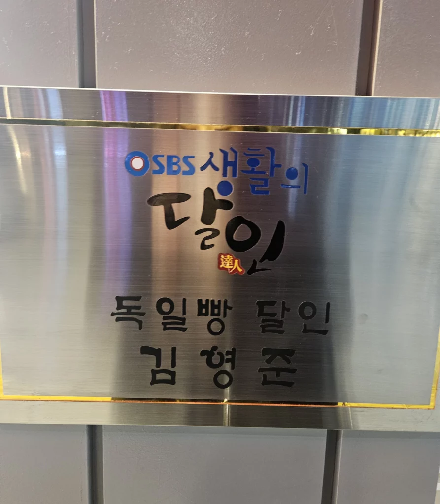 Recognition plaque displayed inside a popular bakery cafe, highlighting media coverage and awards for artisanal bread.