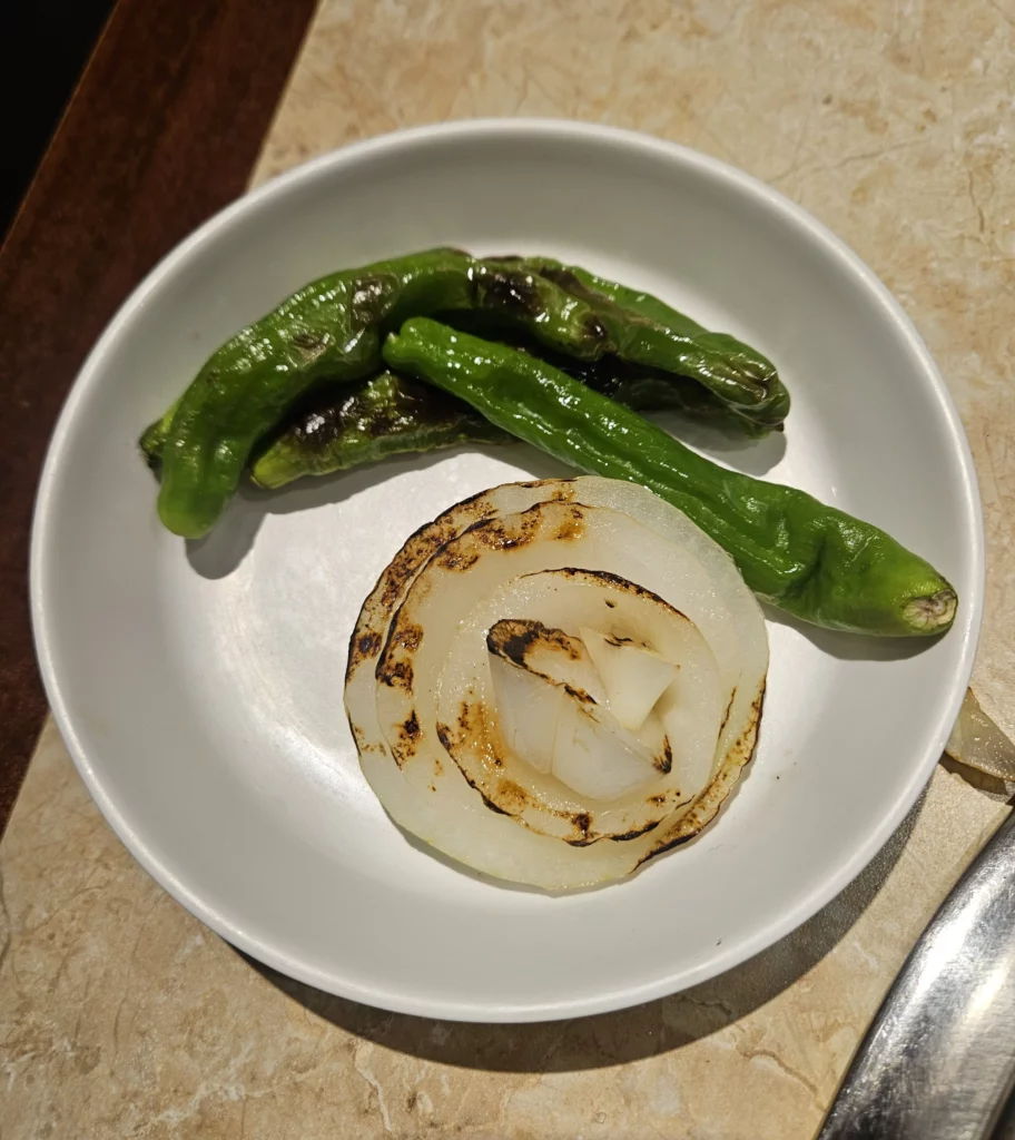 Grilled onion slices and blistered green peppers served as a vegetable side dish with samgyeopsal K-BBQ  at Keum Eun Don.