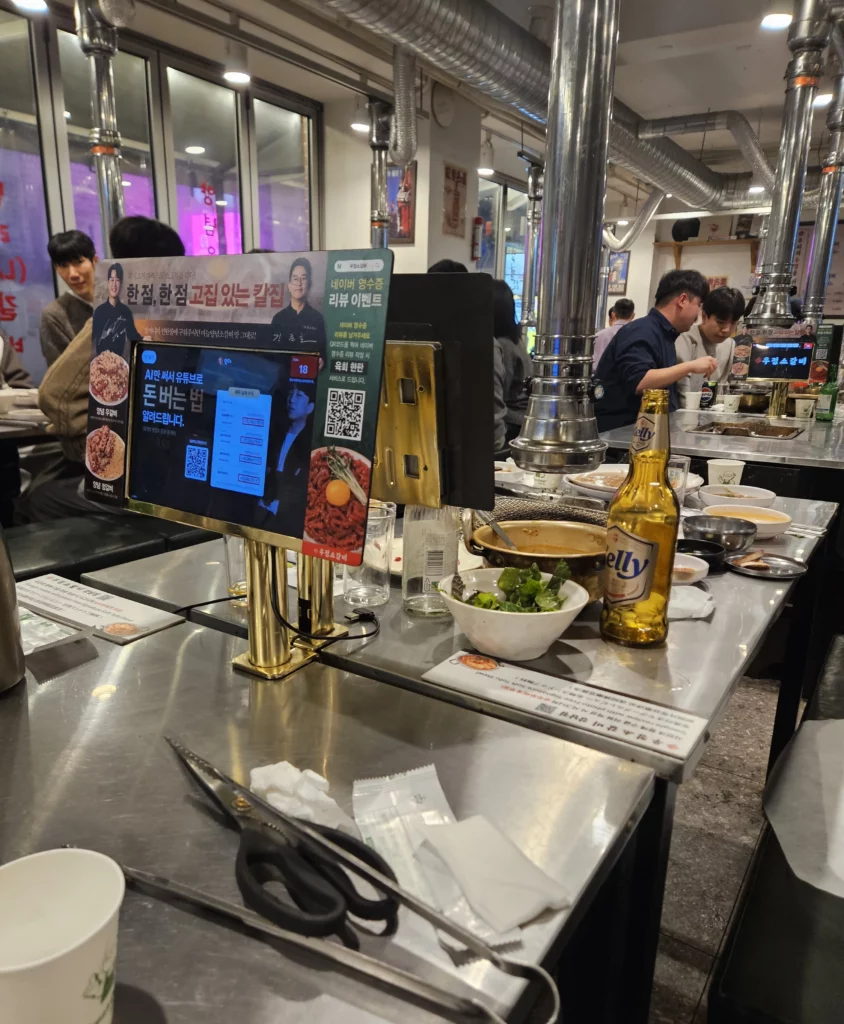 Busy Korean BBQ restaurant interior with table grills, side dishes, and beef korean bbq dining setup.