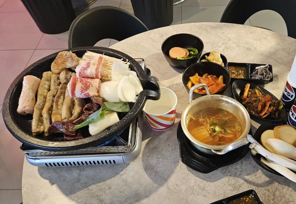 Korean gopchang set served on a tabletop grill with assorted beef intestines, vegetables, soup, and side dishes.