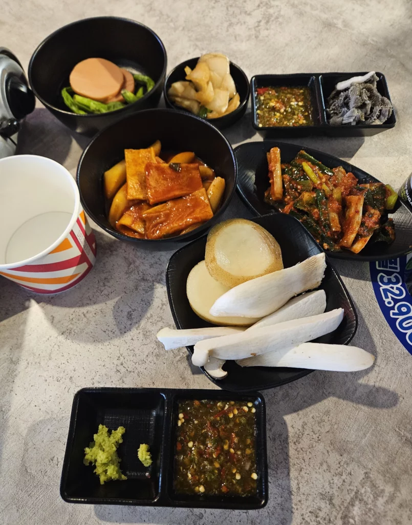 Traditional Korean side dishes and dipping sauces served alongside gopchang, including scallion kimchi and vegetables.