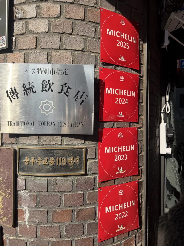 Michelin Guide plaques at Woo Lae Oak Seoul entrance showing consecutive Bib Gourmand recognition from 2022 to 2025 and Traditional Korean Restaurant designation for this historic Pyongyang naengmyeon and bulgogi specialist.