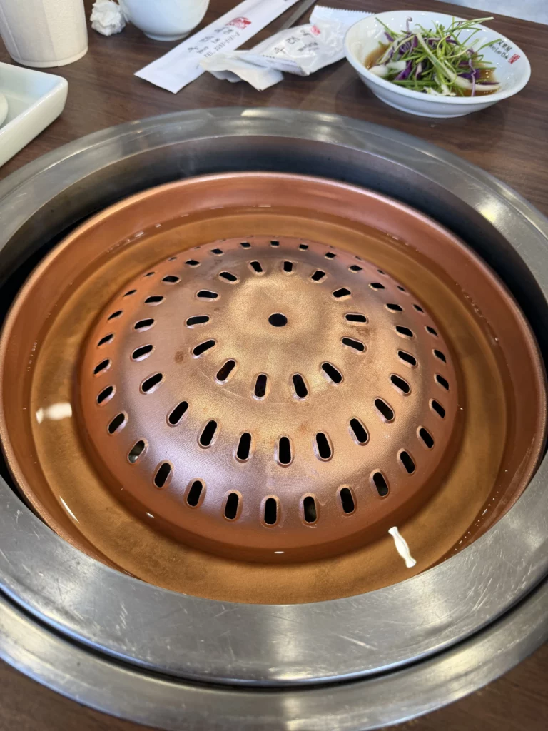 Traditional copper grill used for tableside bulgogi cooking at Woo Lae Oak Seoul, featuring the distinctive domed perforated surface that ensures even heat distribution for grilling premium Hanwoo beef.