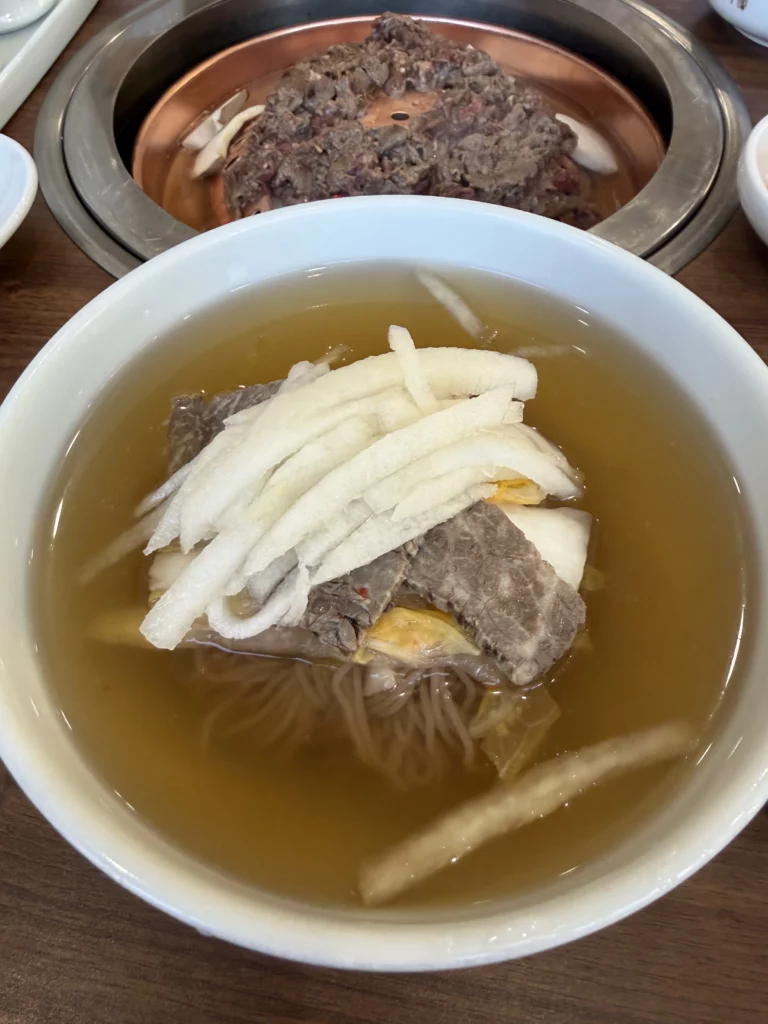 Traditional Pyongyang mul naengmyeon at Woo Lae Oak Seoul, featuring buckwheat noodles in icy beef and dongchimi broth topped with sliced Korean pear, tender beef brisket, and boiled egg in the restaurant's signature cold noodle dish.